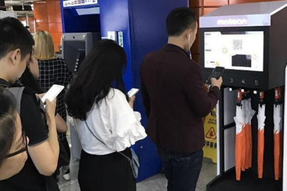 Personas hacen cola mientras utilizan sus teléfonos móviles, en Shanghái.-EFE