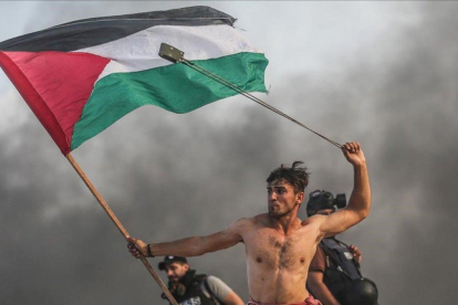 La imagen que se ha convertido en símbolo de la resistencia palestina en Gaza: Aed Abu Amro, con una honda en la mano izquierda y una bandera palestina en la derecha, durante una protesta el 22 de octubre del 2018.-GETTY IMAGES / ANADOLU / MUSTAFA HASSONA