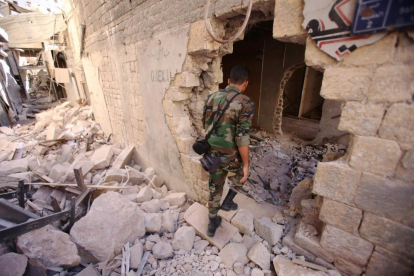 Un soldado del Ejército sirio inspecciona un edificio dañado en Alepo.-AFP / YOUSSEF KARWASHAN