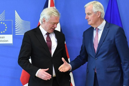 Michel Barnier tiende la mano a David Davis en la sede de la Comisión Europea, en Bruselas.-/ AFP / EMMANUEL DUNAND