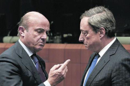 El ministro de Economía español, Luis de Guindos, y el presidente del BCE, Mario Draghi, durante una reunión del Eurogrupo.-EFE / JULIEN WARNAND