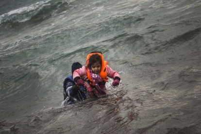 Un hombre ayuda a un niño cuyo barco ha naufragado este domingo en el Egeo.-AFP