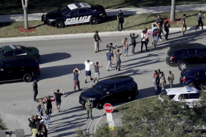 Evacuación de estudiantes con los brazos en alto a la salida del instituto Marjory Stoneman Douglas, en Parkland (Florida), el 14 de febrero.-/ AP / MIKE STOCKER