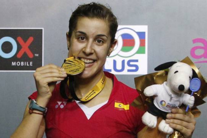 Carolina Marín 'muerde' la medalla de oro que la acredita como ganadora del Abierto de Malasia de bádminton.-Foto: AP / JOSHUA PAUL