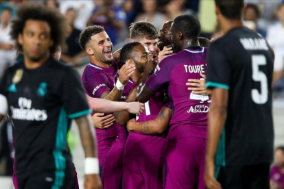 Los jugadores del City celebran un gol ante la mirada de Marcelo y Varane.-AFP / RINGO CHIU