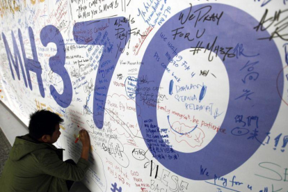 Fotografía de archivo del 13 de marzo del 2014 de un hombre escribiendo mensajes en recuerdo a las víctimas del vuelo MH370 de Malaysia Airlines en el aeropuerto internacional de Kuala Lumpur (Malasia).-EFE