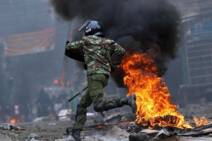 Un agente antidisturbios salta una barricada en llamas levantada por seguidores del opositor Raila Odinga, en Mathare (Nairobi), el 12 de agosto.-REUTERS / THOMAS MUKOYA