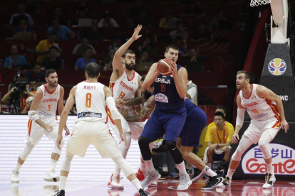 La estrella serbia Nikola Jokic (c) intenta manejar el balón ante la oposición de la defensa española.-