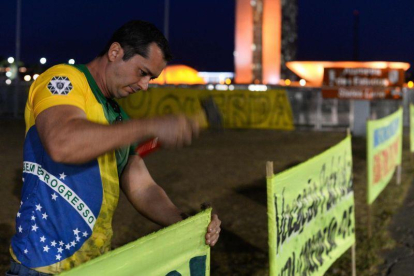 Un partidario de Rousseff clava un cartel en las afueras del senado brasileño.-ANDRESSA ANHOLETE / AP / AFP