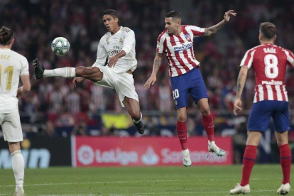 El madridista Varane (i) golpea un balón en el partido ante el Atlético de Madrid.-AP