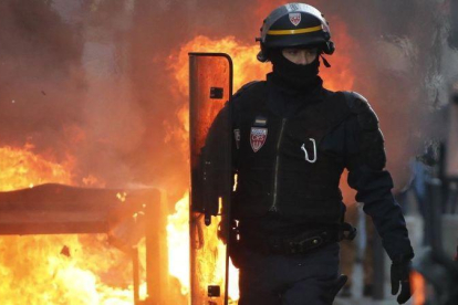 Un policía antidisturbios camina cerca del fuego de una barricada en Toulouse.-EFE / GUILLAUNE HORCAJUELO