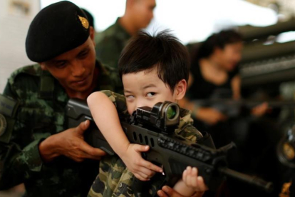 Un soldado tailandés muestra a un niño cómo funciona un arma en la celebración del Día del Niño.-REUTERS / JORGE SILVA