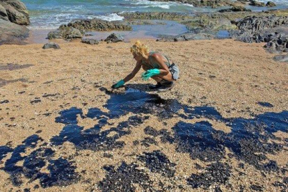 Una voluntaria recoge restos de crudo en la arena de una playa cerca del centro turístico de Oporto de Busca Vida en Lauro de Freitas, estado de Bahía.-ANTONELLO VENERI (AFP)
