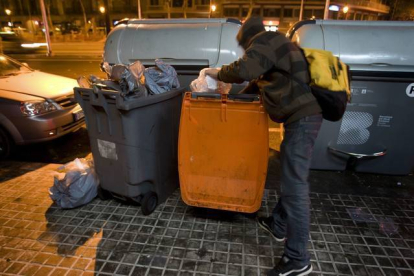 Un joven busca comida en un contenedor de basura orgánica, en Barcelona.-Foto: ALBERT BERTRAN