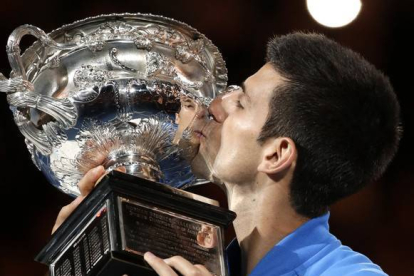 Novak Djokovic besa el trofeo que le acredita como campón del Abierto de Australia.-AP