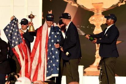 El capitán del equipo estadounidense Davis Love y su vicecapitánTiger Woods celebran en la ceremonia de entrega del trofeo.-TIMOTHY A CLARY / AFP