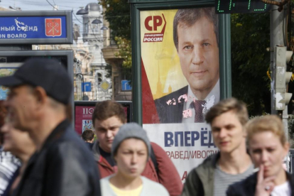 Peatones pasas por delante de un cartel electoral en San Petersburgo.-DMITRO LOVETSKY / AP