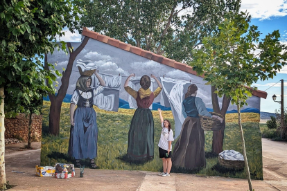 Paula García Rubio junto al mural que ha pintado en Villar del Campo.