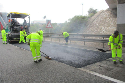 Varios operarios extienden asfalto en una carretera de  Soria.