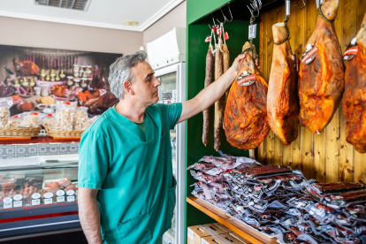 Santiago observa uno de los jamones con su característica cobertura de pimentón en la tienda de Sorama en Matalebreras.