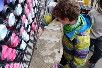 Un niño coloca una lata pintada para configurar un mural de 'mosaico' en una actividad de 'Dar la lata'.