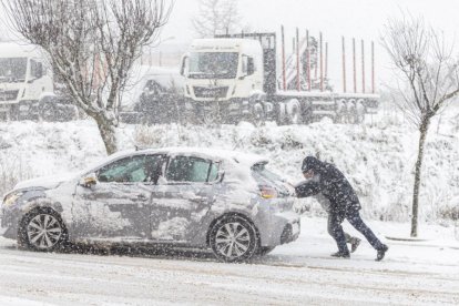 Dos personas empujan un coche durante el paso de la borrasca 'Juan'.