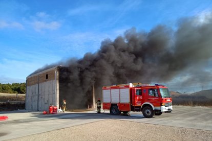 Los bomberos intervienen en la nave ante una densa humareda negra.