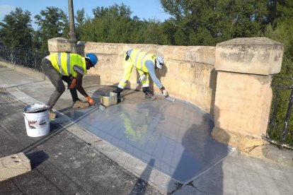 Operarios trabajando sorbe el puente de San Esteban.