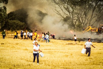 Los vecinos corren con cubos y garrafas mientras un tractorista trata de cortar el avance del fuego en la tarde del 25 de agosto de 2000.