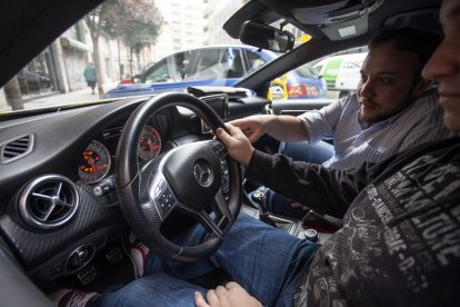 Un profesor explica dentro del coche de una autoescuela a un alumno.