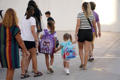 Archivo - Niños y padres hacen cola para entrar al colegio el primer día de clase.