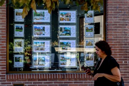 Archivo - Una mujer camina frente a un escaparate de anuncios de viviendas, a 4 de agosto de 2023, en Madrid (España). La compraventa de vivienda en España disminuye un 6,4% interanual por el retroceso de las operaciones sobre los inmuebles usados, según.