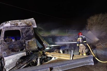 Un bombero trabaja para enfriar el camíón de mercancías peligrosas calcinado tras el accidente.