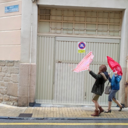 Dos jóvenes 'pelean' con sus paraguas en Soria durante un temporal de viento.-HDS