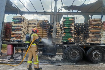 Un bomberos refresca el remolque afectado.