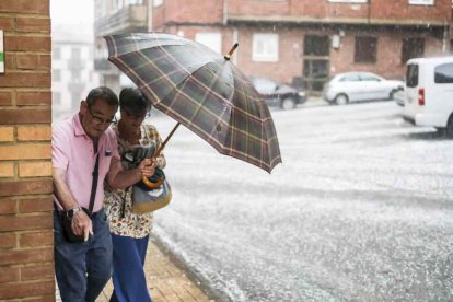 Dos personas luchando contra el viento con un paraguas.