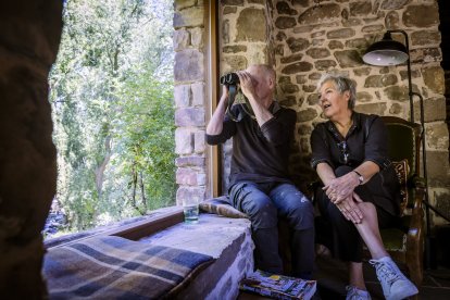 La pareja, en el salón de su vivienda que han reconstruido, mirando por un enorme ventanal las aves de su jardín.