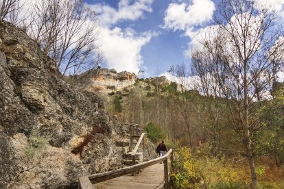 El acceso a La Fuentona transcurre por un sendero fluvial entre montañas calizas, vegetación estacional y pasarelas de madera.