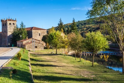 La iglesia parroquial de Salduero se asoma al Duero en un entorno verde y abierto, con los pinares de la Sierra de Urbión cerrando el horizonte.