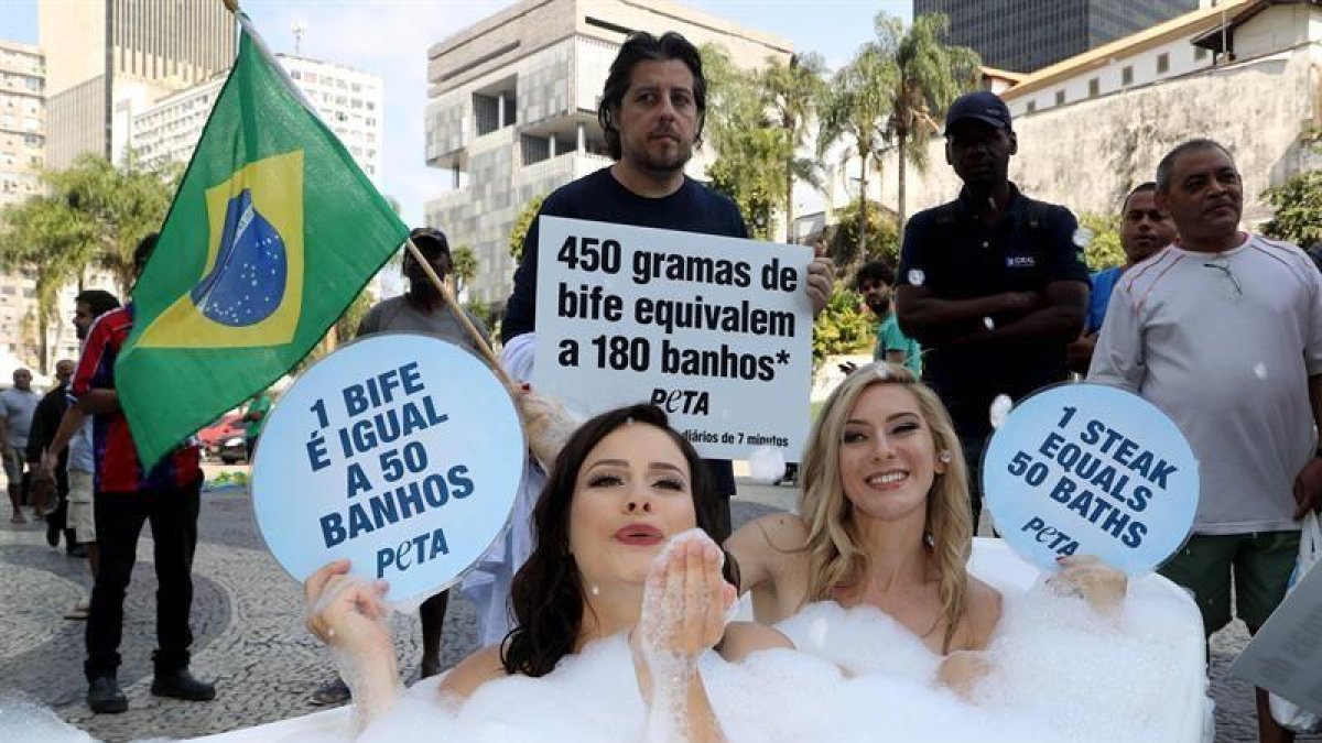 Dos activistas de la organización Personas a favor del Trato Ético a los Animales (PETA, en inglés) se bañan en una tina en el centro de Río de Janeiro hoy para denunciar que el consumo de carne supone el despilfarro de grandes cantidades de agua.-EFE / Fernando Maia