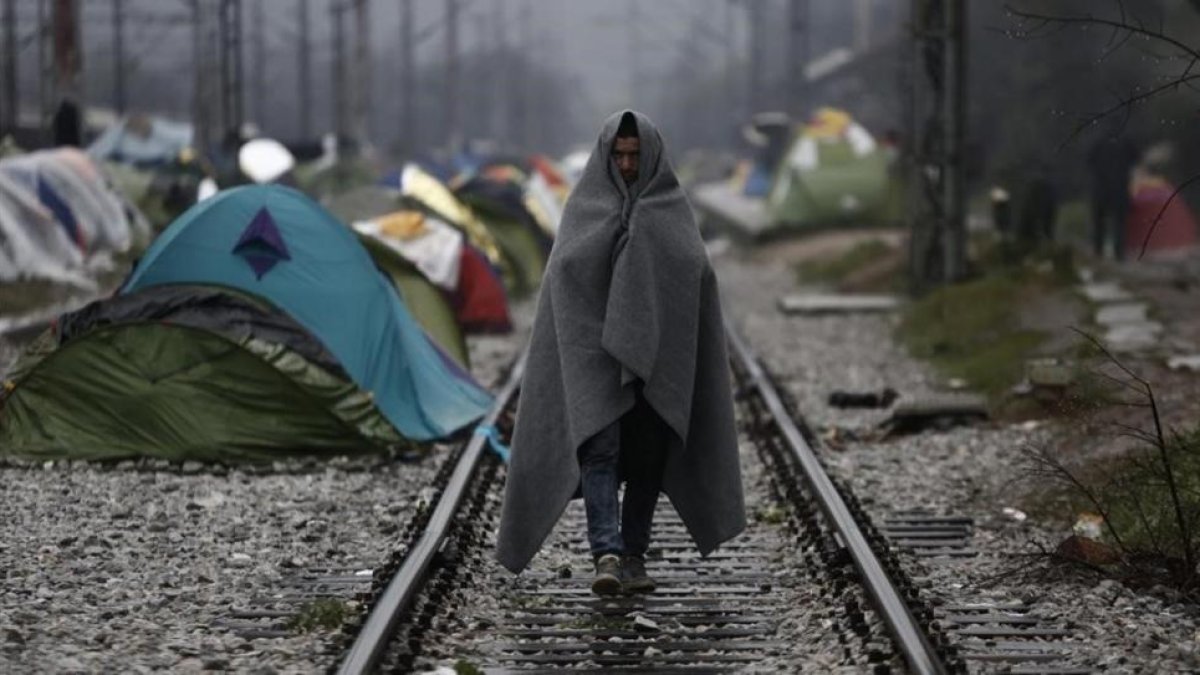 Un refugiado envuelto en una manta, en un campo de refugiados en la frontera entre Grecia y Macedonia, cerca de Idomeni (Grecia), este jueves.-EFE / YANNIS KOLESIDIS