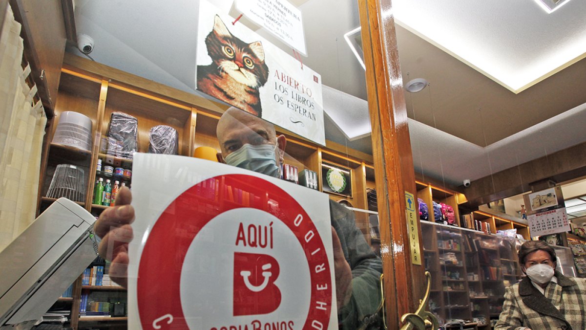 César Millán, de la librería Las Heras, coloca el distintivo de Soria Bonos. MARIO TEJEDOR