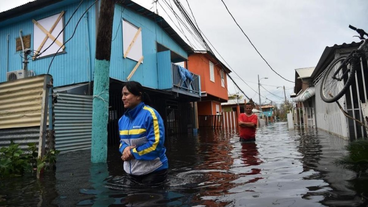 Dos personas caminan por una calle inundada en Juana Matos (Puerto Rico), el 21 de septiembre.-AFP / HECTOR RETAMAL