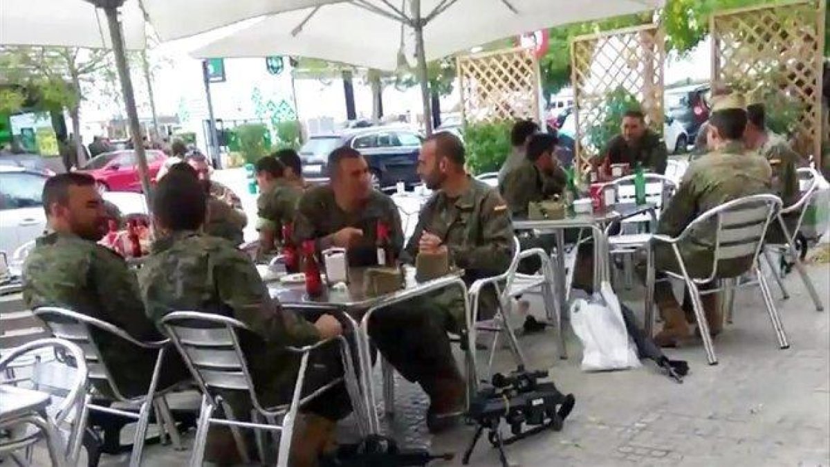 Legionarios tomando unas cervezas junto a sus armas en una terraza.-