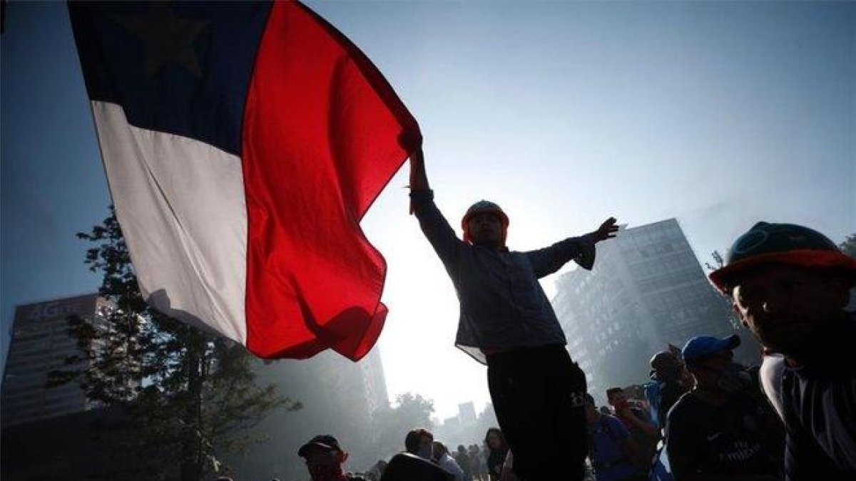 Una personas porta la bandera de Chile en medio de las protestas sociales.-EFE