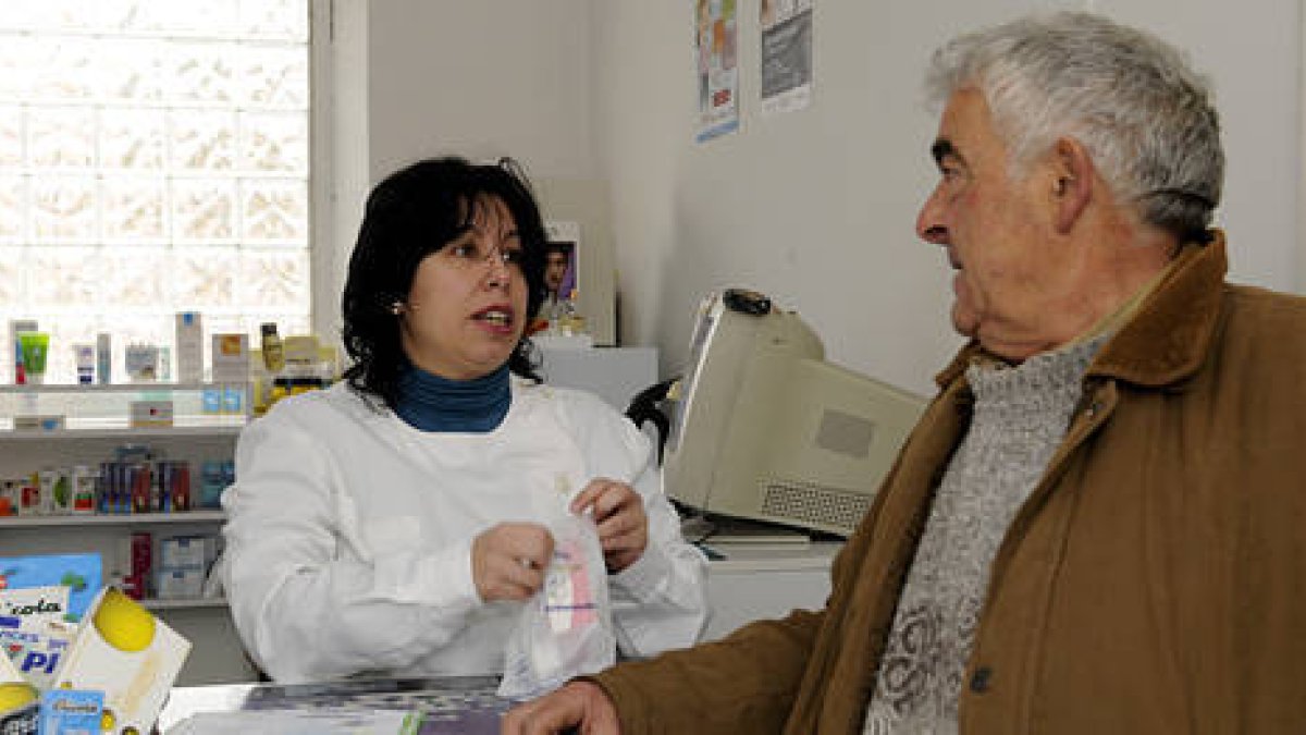 Francisca Castro Corada, Kika, atendiendo a un cliente en su farmacia de Matamala de Almazán. / VALENTÍN GUISANDE-