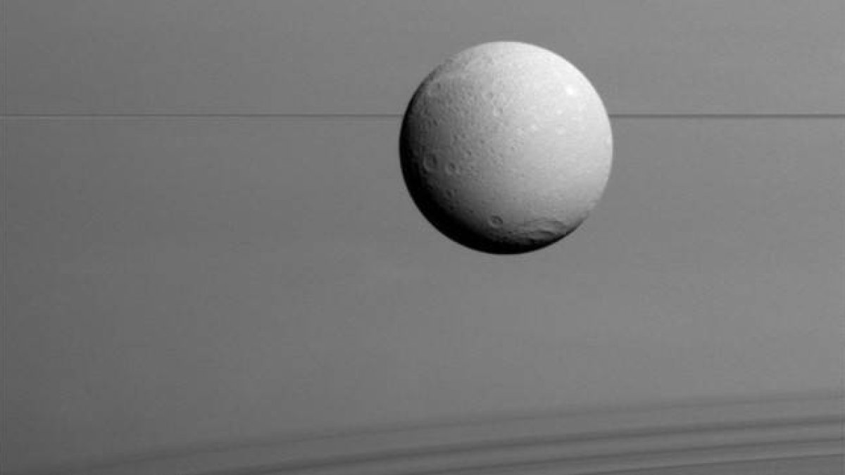 Panorámica de Dione con los anillos de Saturno al fondo.-Foto:  NASA / ESA