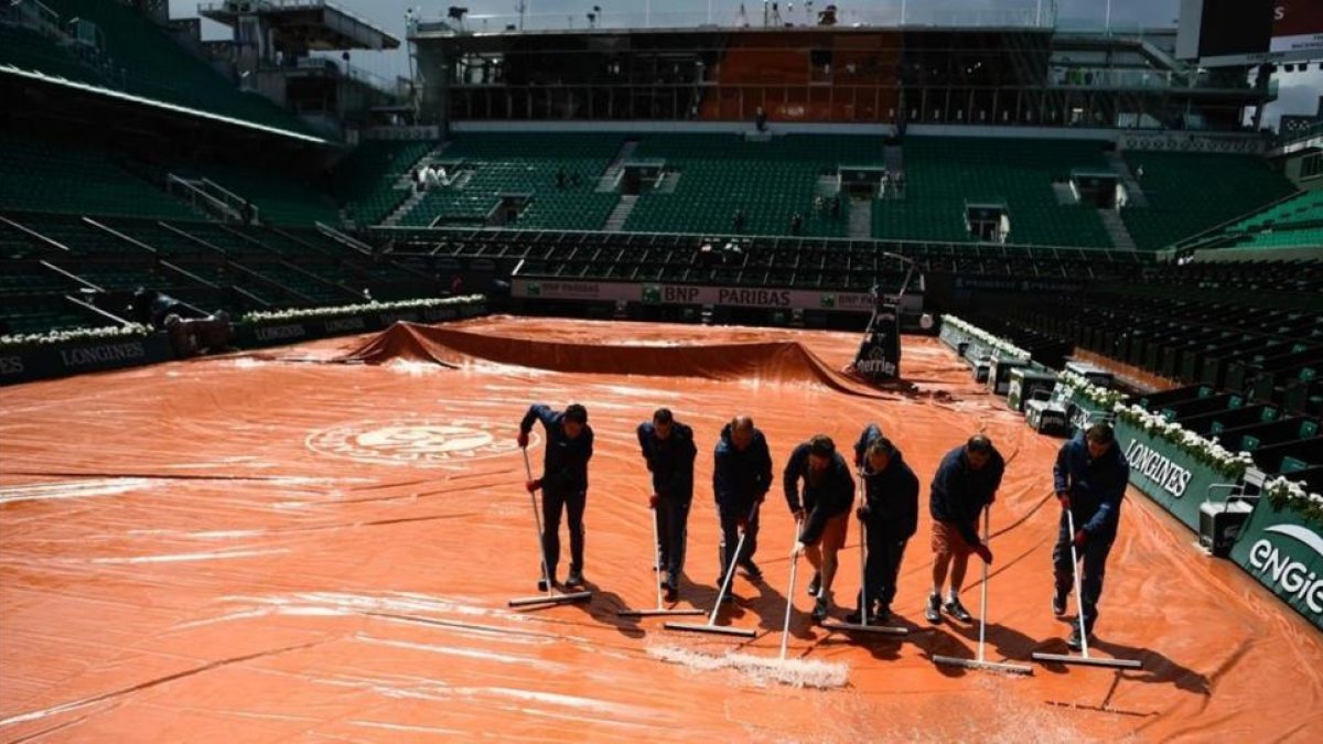 Operarios achican el agua en la central de Roland Garros.-AFP / CHRISTOPHE SIMON