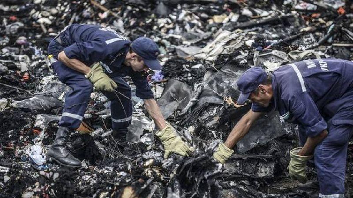 Dos agentes buscan entre los restos del vuelo MH17 de Malaysia Airlines.-AFP / BULENT KILIC