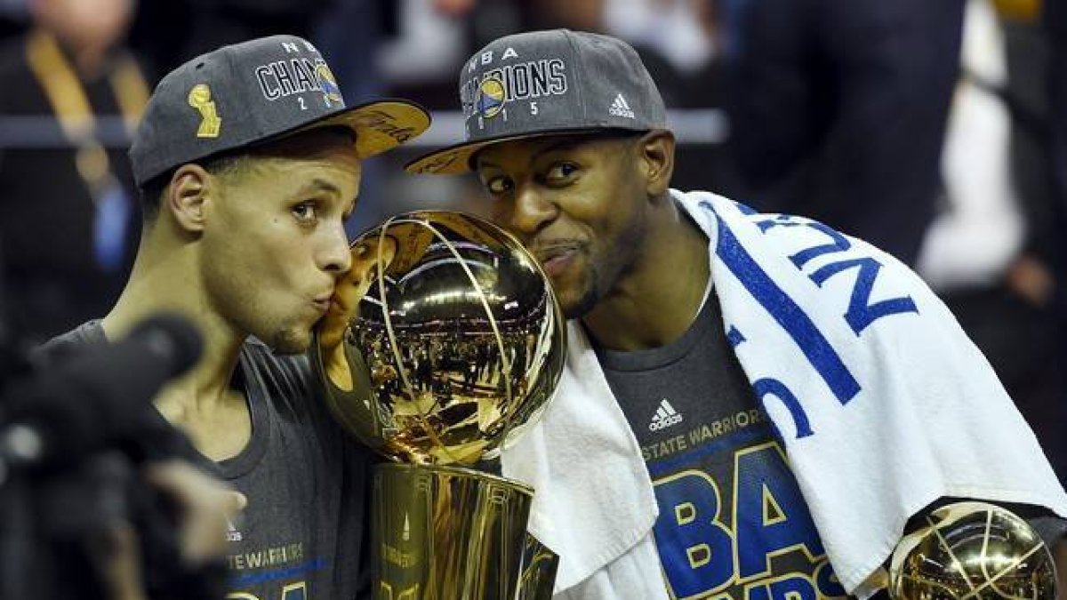 Stephen Curry y Andre Iguodala besan el título de campeones de la NBA.-BOB DONNAN